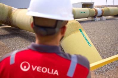 Back technician looking at examining a yellow pipe in a desalination plant